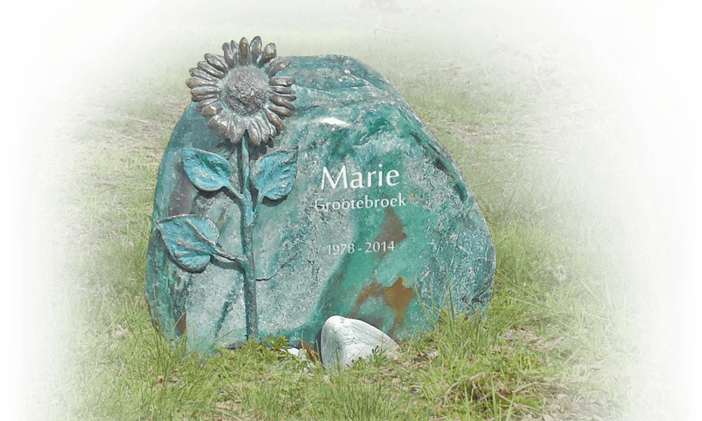 grafzerk natuurbegraafplaats zwerfkei met bronzen zonnebloem